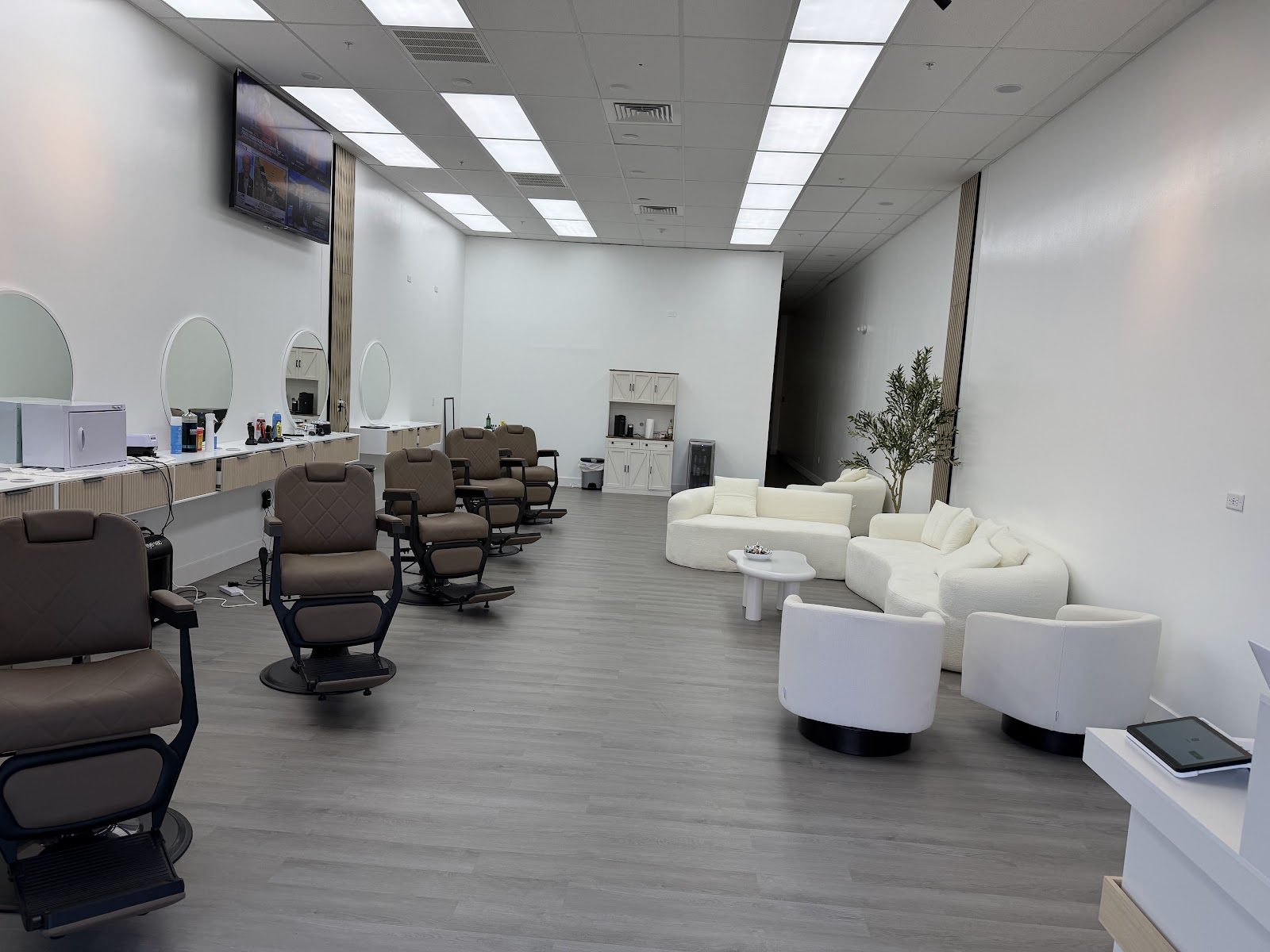 Inside The People's Barbershop in Naples — bright studio with espresso leather chairs, halo mirrors and a boucle lounge